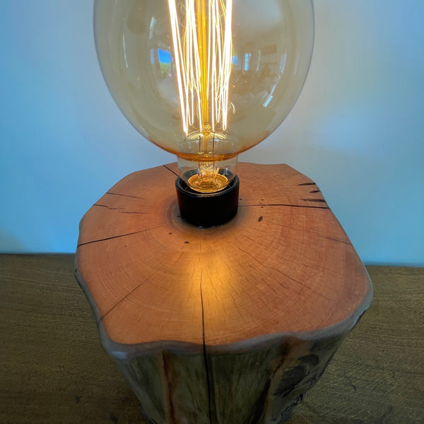 Wood table lamp handcrafted by shades at grays from authentic tōtara post,  smooth polished wood grain of top and light reflection.