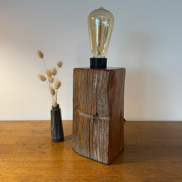 Wooden lamp with a vintage-style light bulb on a wooden surface.