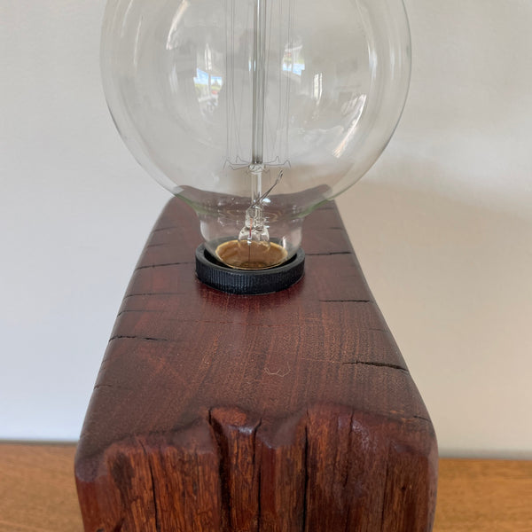 Wood table lamp handcrafted by shades at grays from wharf timber unlit, close up of smooth top.