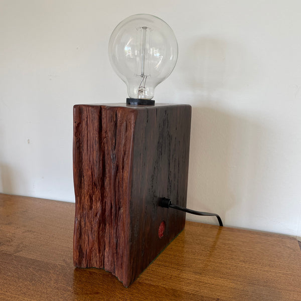 Wood table lamp handcrafted by shades at grays from wharf timber with original bolt and replica edison bulb, unlit, back view