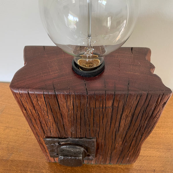 Wood table lamp handcrafted by shades at grays from wharf timber with original bolt and replica edison bulb, unlit, smooth top and front view.