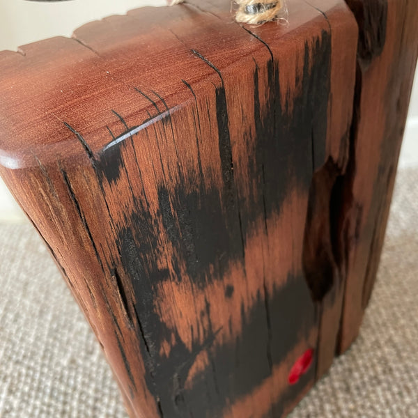 Wood door stop with authentic tar marks and erosion grooves, and polished railway pandrol clip, crafted by shades at grays, close up of back and top view.