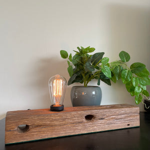 Wood table lamp crafted by shades at grays from telegraph cross piece, lit.