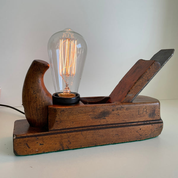 Carpenter's initials still visible on old wood plane upcycled into a unique wooden table lamp.