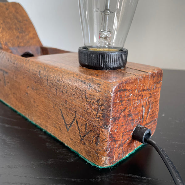 Wooden table lamp crafted from vintage carpenter's plane, cleaned and polished, view of initials carved in to plane and black lead.