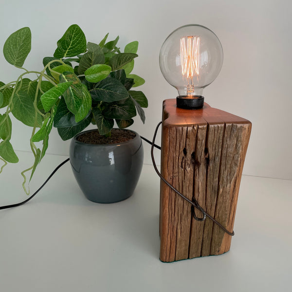 Wooden table lamp handcrafted from rustic totara fence post, by shades at grays, lit.