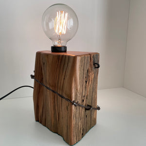 Wooden table lamp handcraafted from totara post with original fence wire, side view.