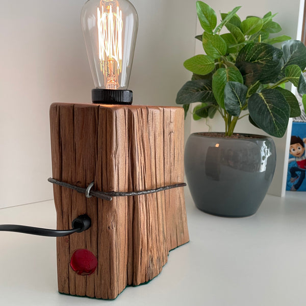 Wooden table lamp handcrafted from vintage totara post with original wire and replica edison bulb, back view.