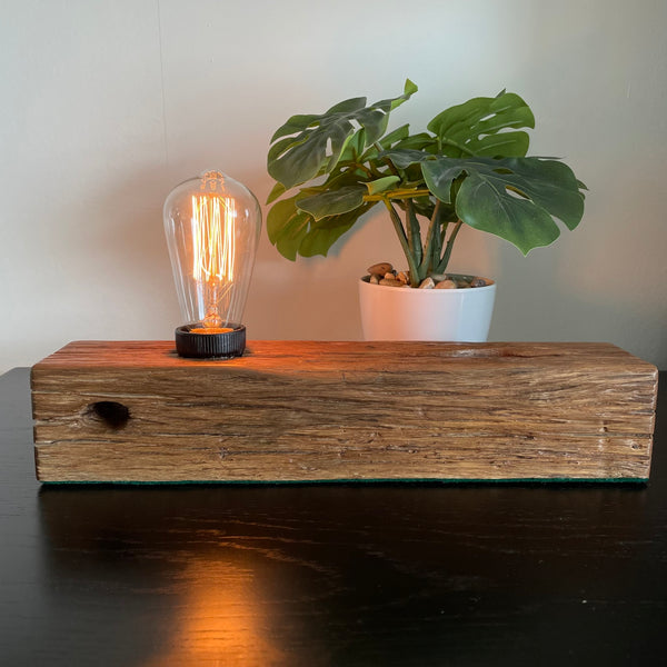 Wooden table lamp upcycled by shades at grays from old telegraph post, front view, lit.