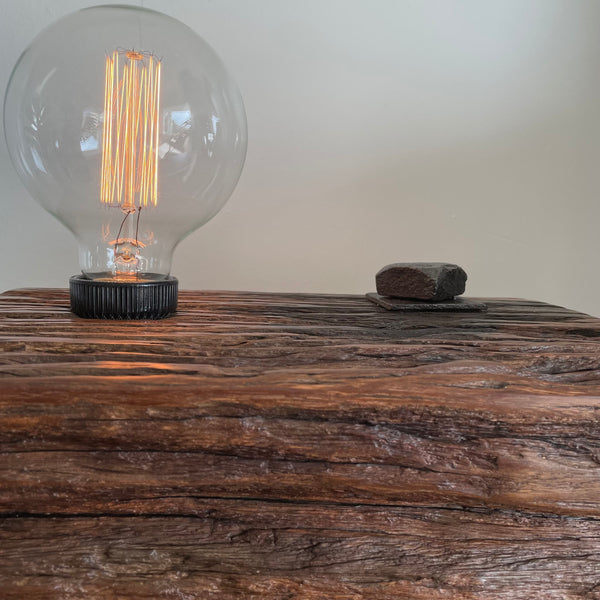 Wooden table lamp upcycled from wharf timber with addition of replica edison bulb, close up of eroded grooves. 