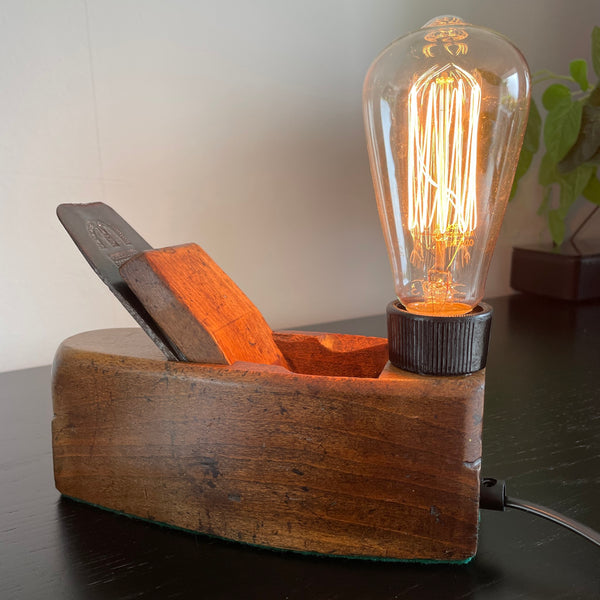 Wood lamp created by shades at grays from vintage wood plane, back view, lit.
