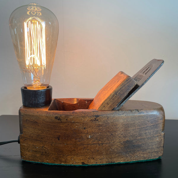 Wood lamp created by shades at grays from vintage wood plane, front view, lit.