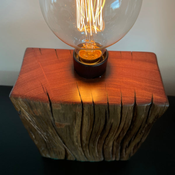 Unique timber wood lamp created from reclaimed wharf timber, lit, clos eup of top polished with natural bees wax.