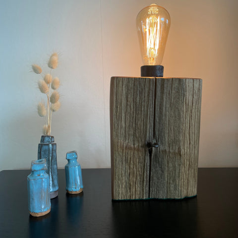 Wood table lamp crafted by shades at grays from old totara post with original staple, lit.