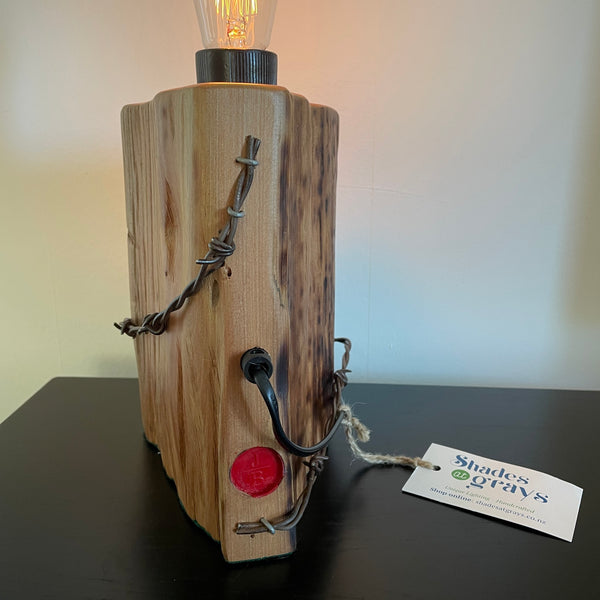 Wood table lamp crafted from reclaimed tōtara post with authentic barbed wire and the adition of an edision bulb, back view by shades at grays.