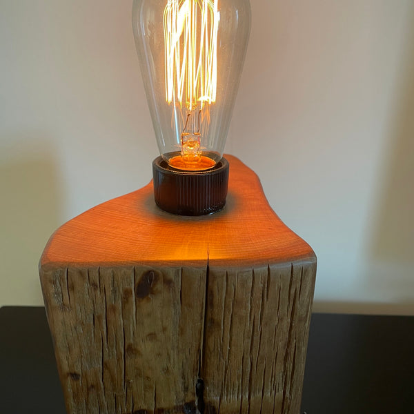 Wood table lamp crafted from reclaimed tōtara post with authentic barbed wire and the adition of an edision bulb, close up of smooth polished top, by shades at grays.