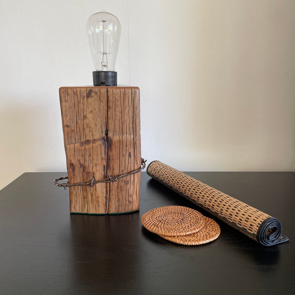 Wood table lamp crafted from reclaimed tōtara post with authentic barbed wire and the adition of an edision bulb, unlit, by shades at grays.