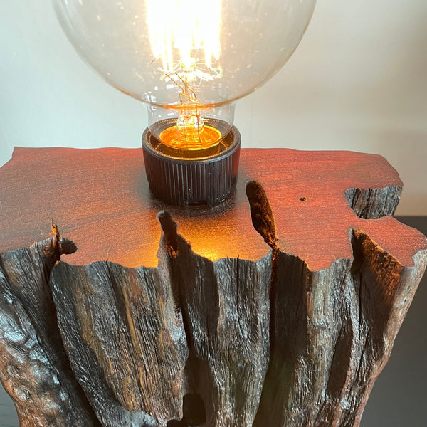 Wood table lamp from reclaimed railway sleeper, with natural erosion and replica edison lamp crafted by shades at grays, close up of polished top.