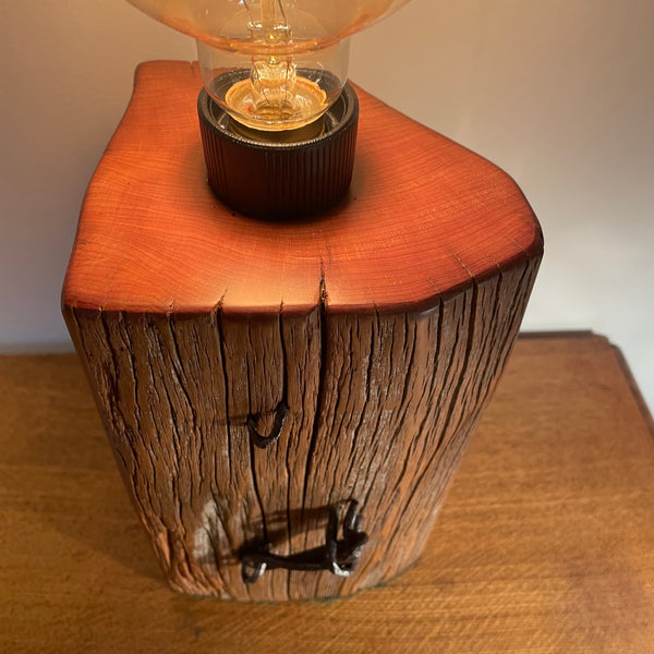 Wood table lamp handcrafted by Shades at Grays from authentic tōtara post, edison bulb, lit, close up of smooth top grain.