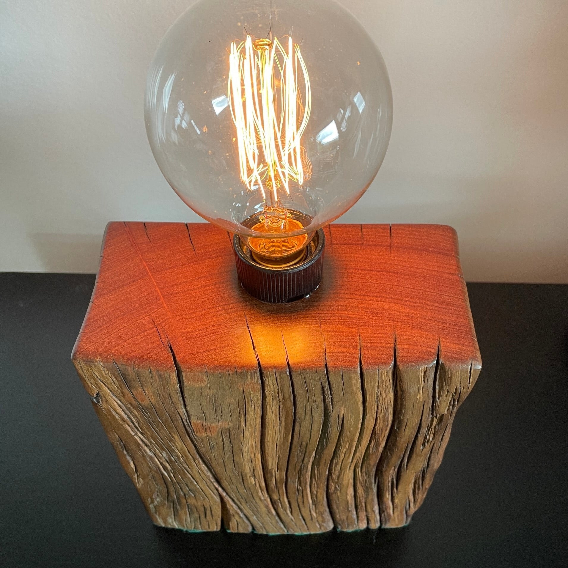 Unique timber wood lamp created from reclaimed wharf timber, lit, polished top and front view.