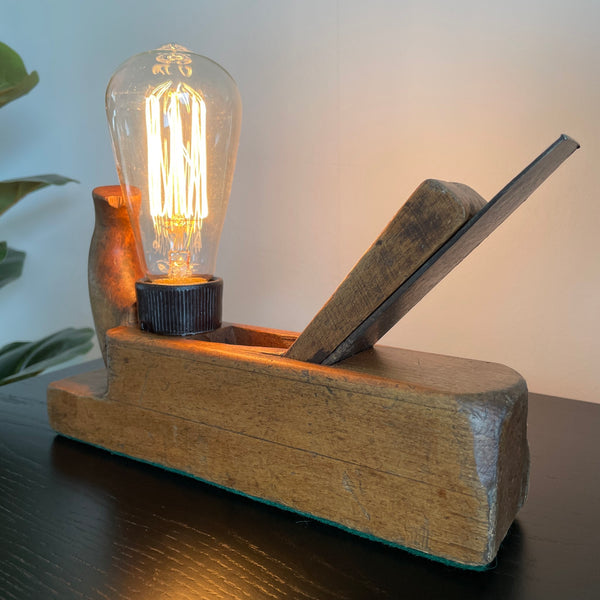 Wood table lamp made from vintage wood block with replica edison bulb, by shades at grays, angled front view, lit