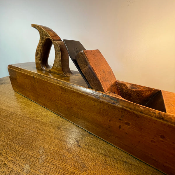Wooden plane tool on a wooden surface with a neutral background