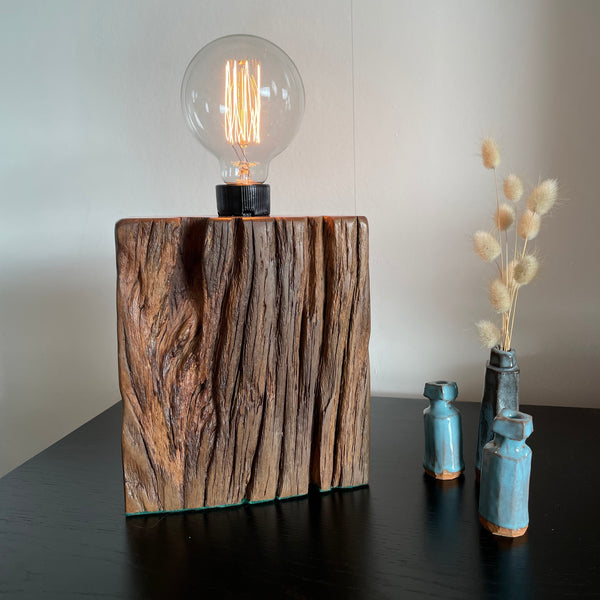 Wood table lamp upcycled from wharf timber, with edison lightbulb, lit, front view, crafted by shades at grays.