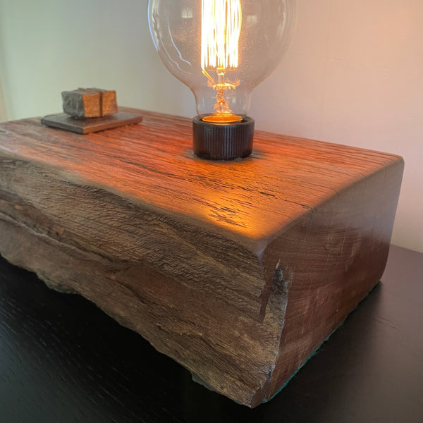 Wood table lamp upcycled from wharf timber with original bolt and edison bulb, close up of front, top and side by shades at grays.