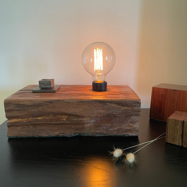 Wood table lamp upcycled from wharf timber with original bolt and edison bulb, lit, by shades at grays.