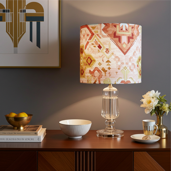 Decorative lamp with geometric pattern on a wooden table with books, bowl, and flowers.