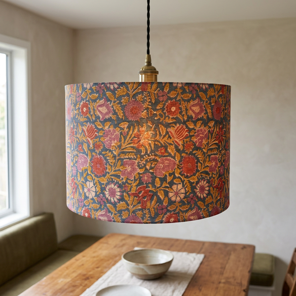 Blue floral drum lampshade styled as a ceiling pendant above a timber dining table