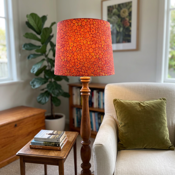 Button Mosaic Orange lampshade on a floor lamp beside a cream armchair