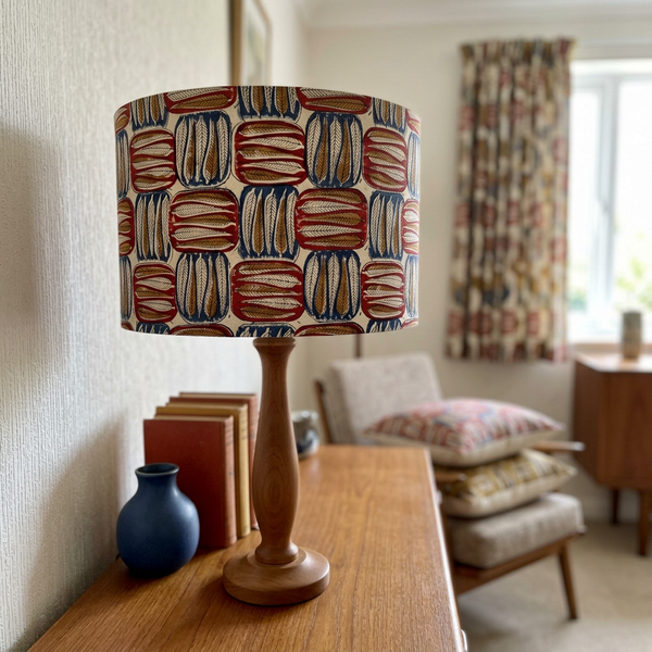 Unlit drum lampshade in Spear Leaf Spice fabric on a timber base in a mid-century living room