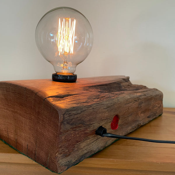 Back edge and right hand side of Handcrafted wharf timber table lamp with edison light bulb and black lead.