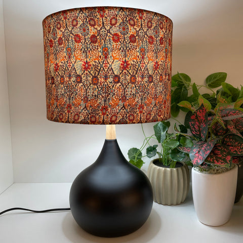 Black touch lamp with handcrafted fabric lamp shade, lit.