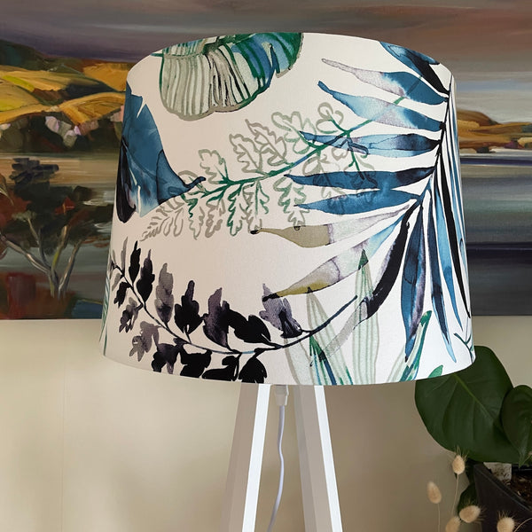 Blue green foliage on white background create unique handcrafted fabric lampshade on white wooden lamp base