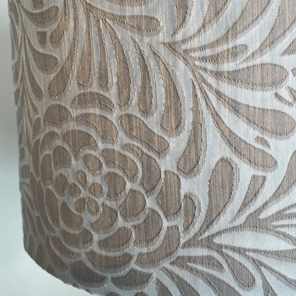 Bottom edge of large drum fabric light shade with silver swirl pattern. 