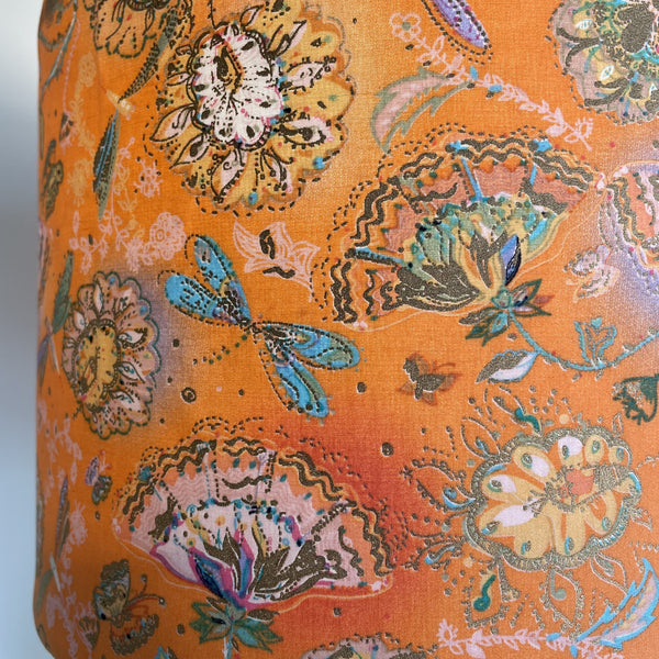 lose up of delicate dragonflies and blossom on tangerine background, handcrafted lightshade, lit