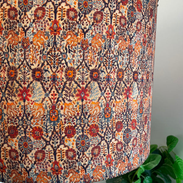 Close up of paisley pattern fabric in rich reds and orange colours.