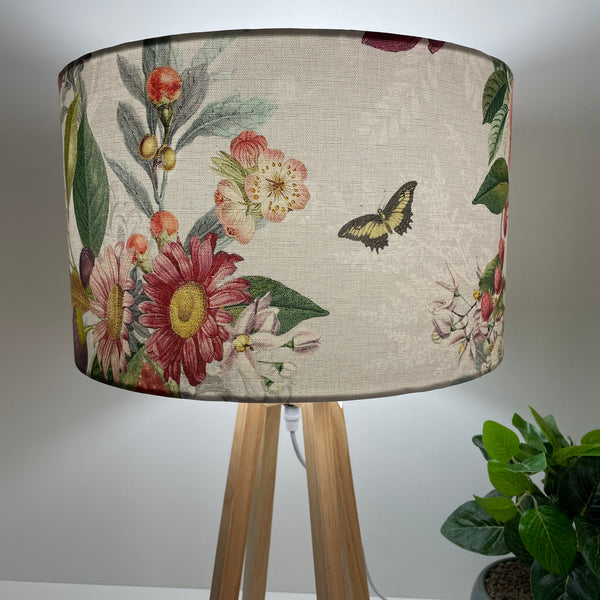 Contemporary natural wood table lamp with handcrafted fabric lampshade, lit, close up.