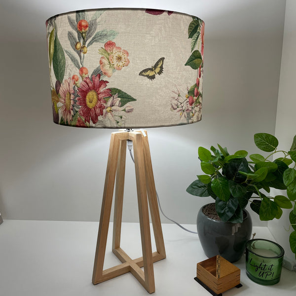 Contemporary natural wood table lamp with handcrafted fabric lampshade, lit.