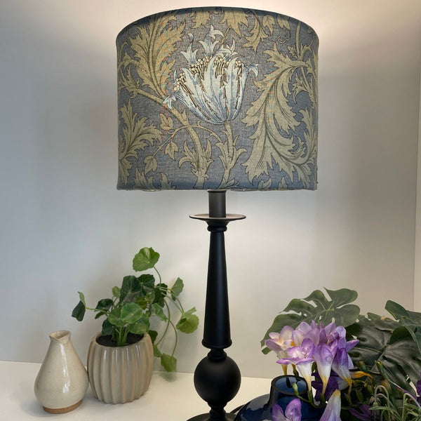 Blue and sage green floral and leave pattern. Morris and Co Anemone light blue. Bespoke fabric lampshade. Lit on black table lamp basae.