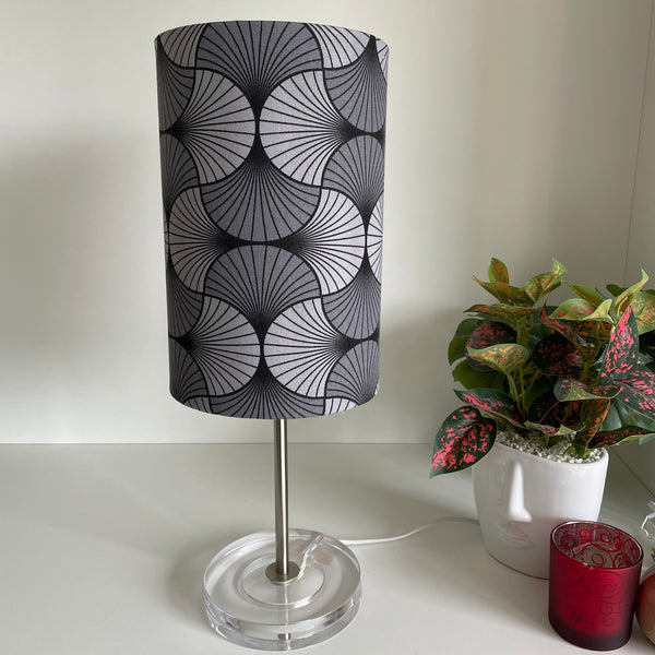 Grey geometric moon lampshade, unlit on silver table stand..