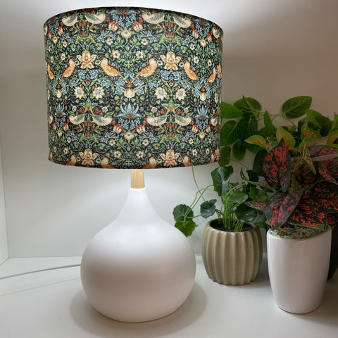 Handcrafted lamp shade on white touch lamp base, lit.