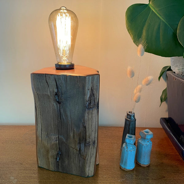 Handcrafted timber table lamp from old totara post with lit edison light bulb