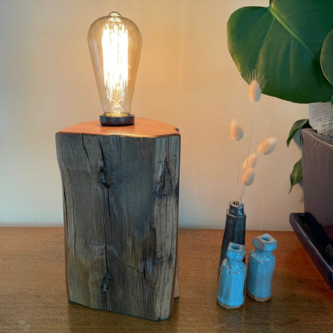 Handcrafted timber table lamp from old totara post with lit edison light bulb