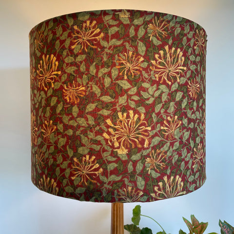 Large barrel handcrafted lampshade with William Morris honeysuckle deep red fabric, lit.