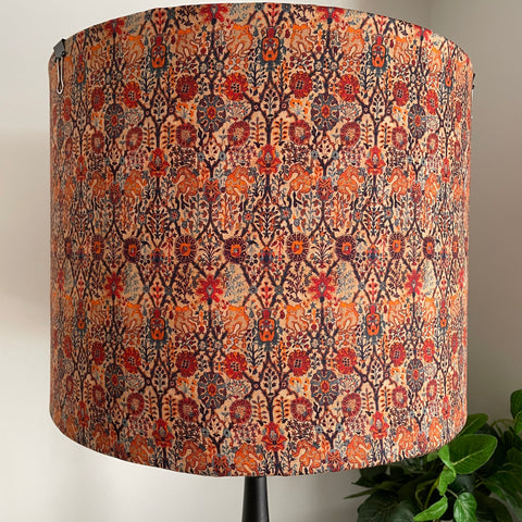 Large drum fabric light shade in warm reds and oranges in a paisley pattern, unlit.