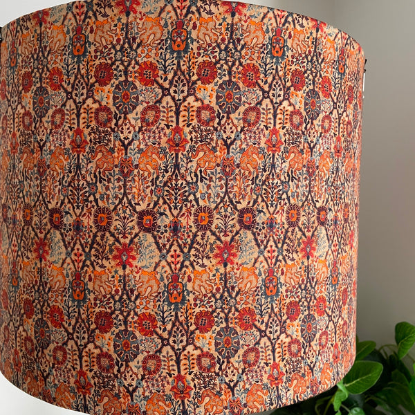 Large drum fabric light shade in warm reds and oranges in a paisley pattern, unlit, close up.