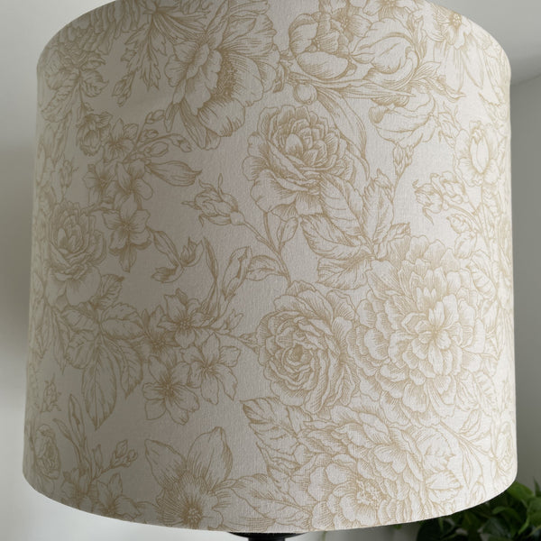 Large drum fabric light shade with flowers etched in gold on cream background, unlit.